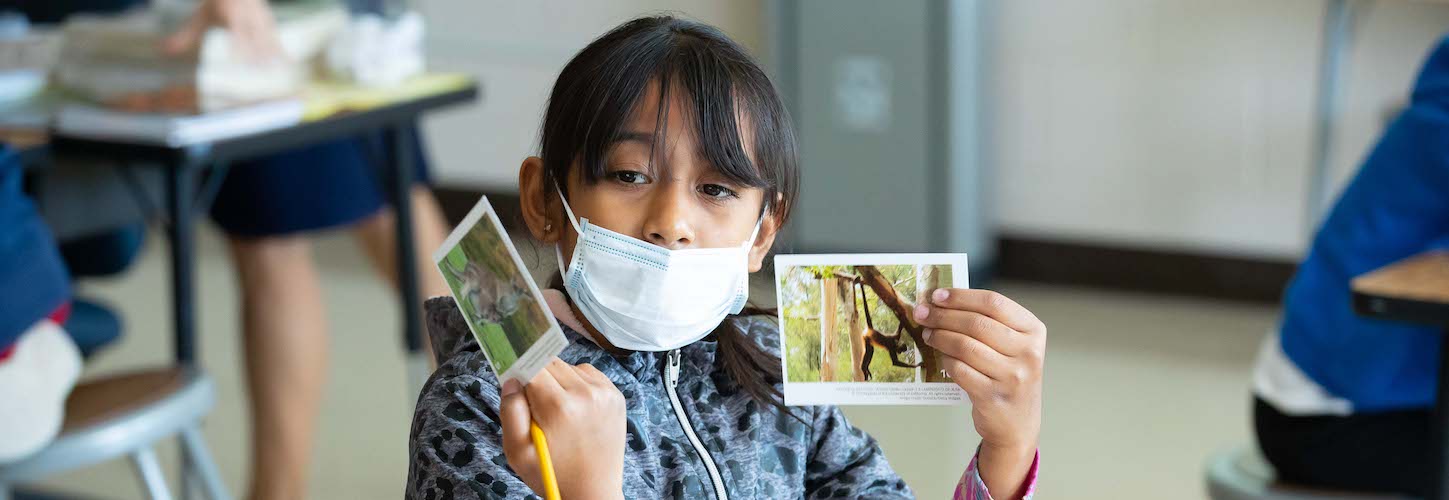 Student holding two pictures up